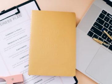 a sheet with a business plan, a notebook and a laptop